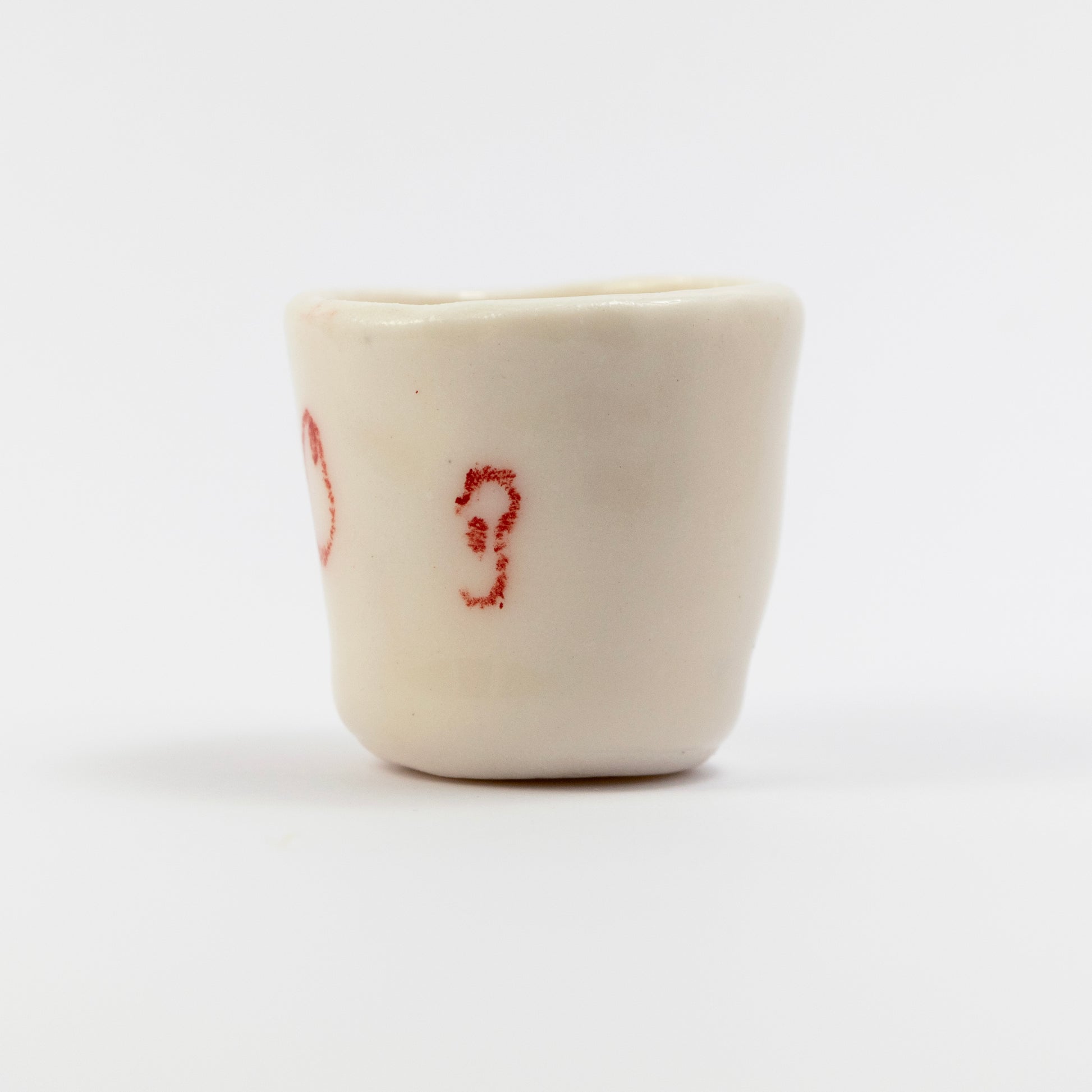 Side of the cup showing a red underglaze pencil doodle resembling an ear.