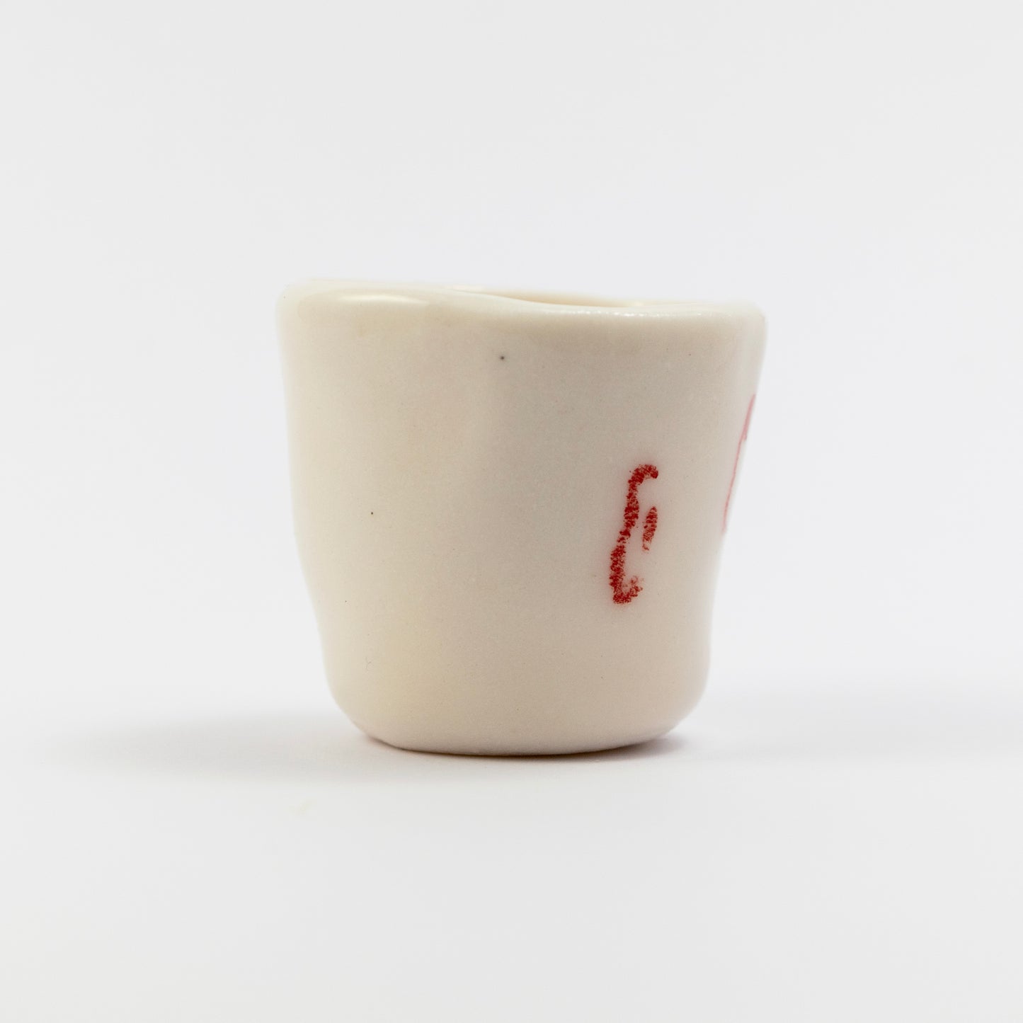 Side of the cup showing a red underglaze pencil doodle resembling an ear.