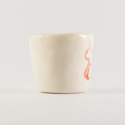 Front view: A ceramic shot glass with hand drawn cartoon horse.