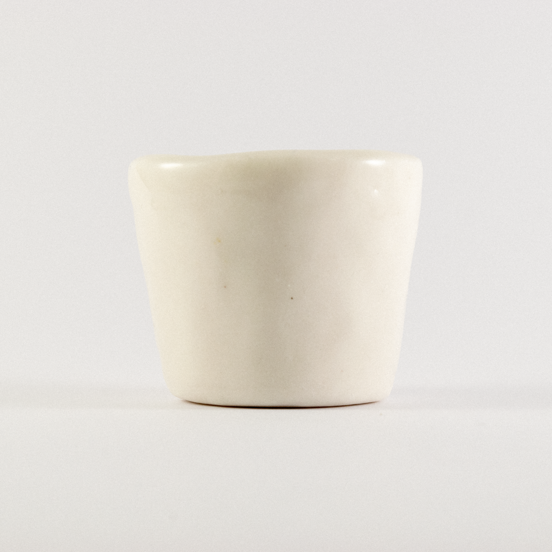 Front view: A ceramic shot glass with hand drawn cartoon horse.