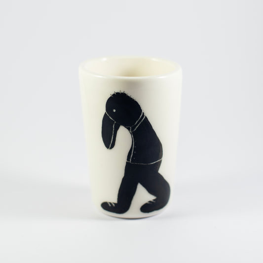Porcelain cup with a tall, tapered shape and a hand-painted black figure on one side, set against a plain white background.